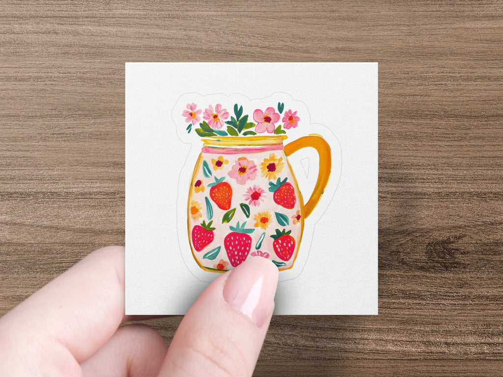 Jar illustration with strawberries and pink flowers, held by a hand.
