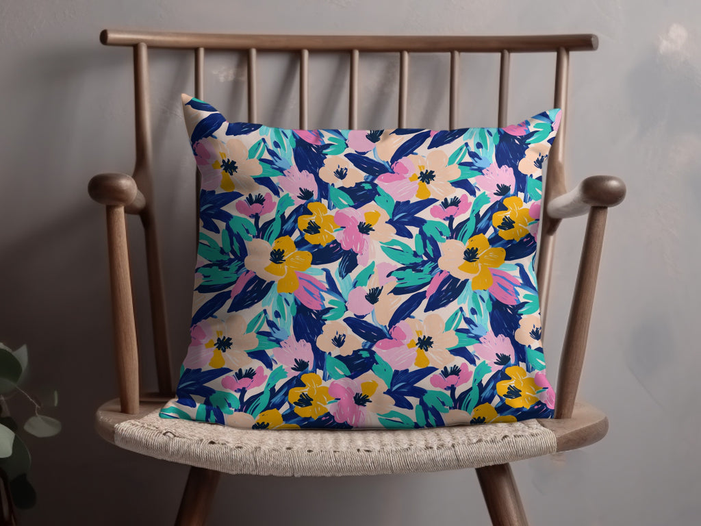 Floral print throw pillow with pink, yellow, and blue flowers on a chair.
