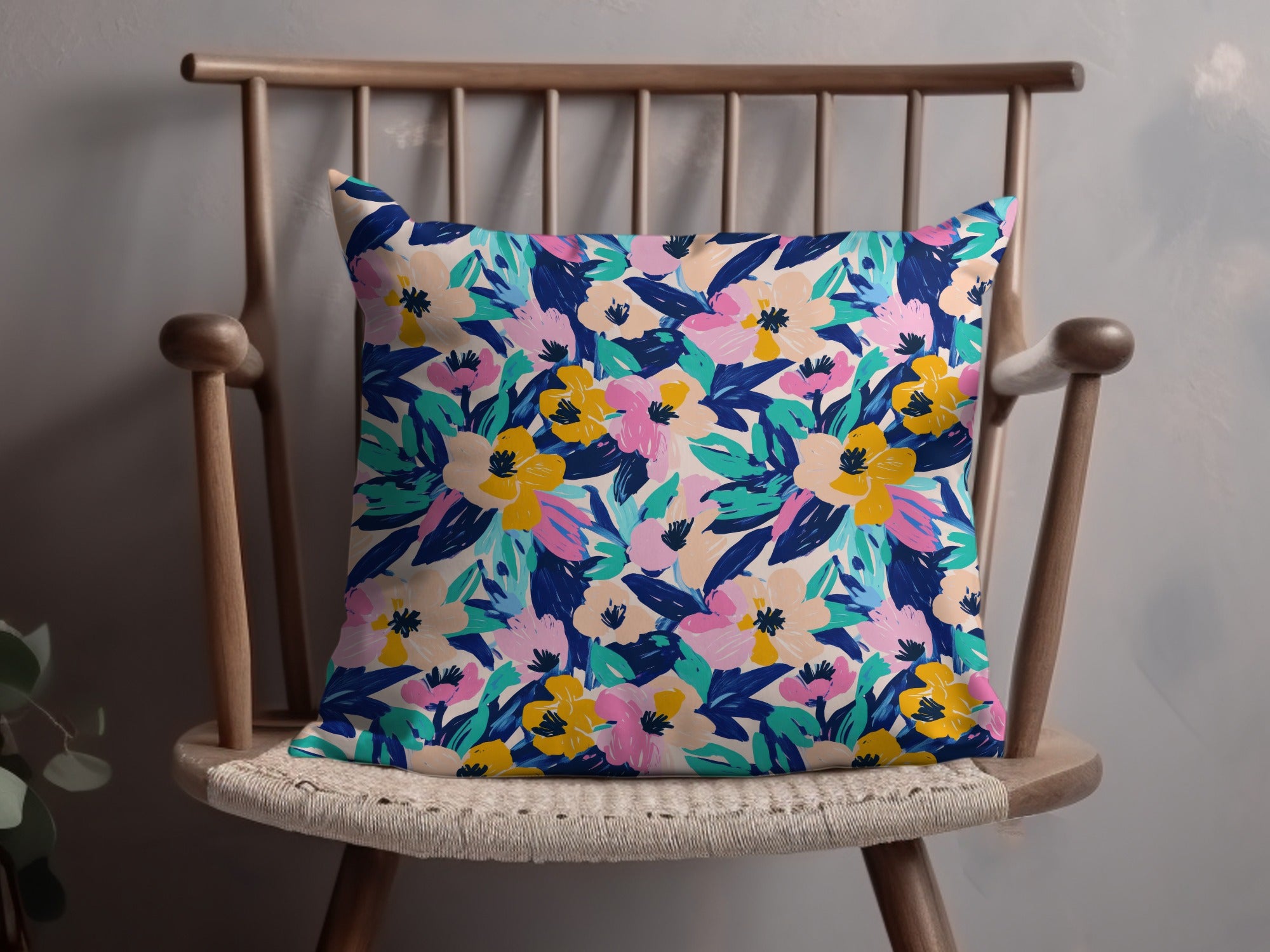 Floral print throw pillow with pink, yellow, and blue flowers on a chair.