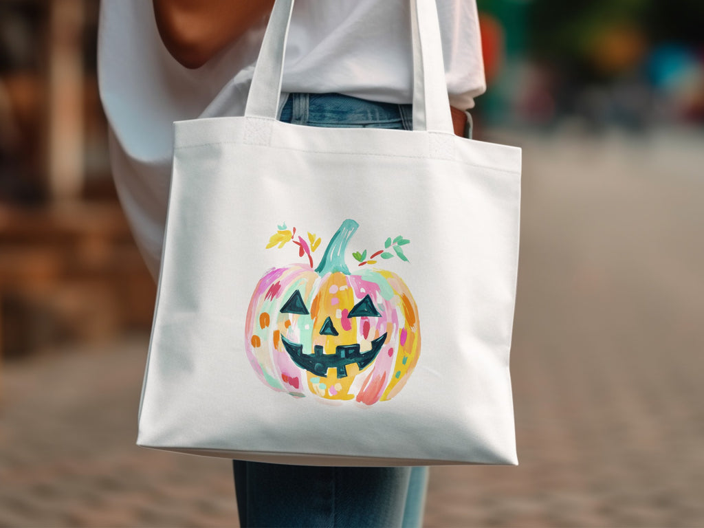White tote bag with a colorful watercolor jack-o'-lantern illustration.