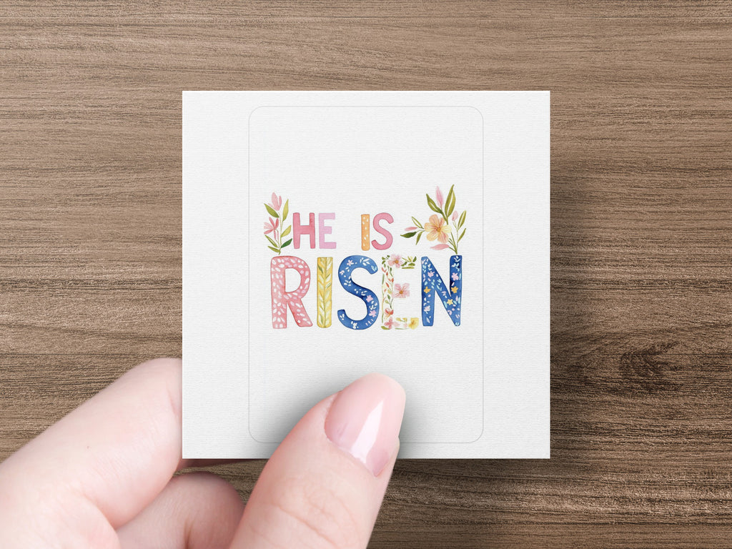 Square sticker with "He Is Risen" text and floral decorations.