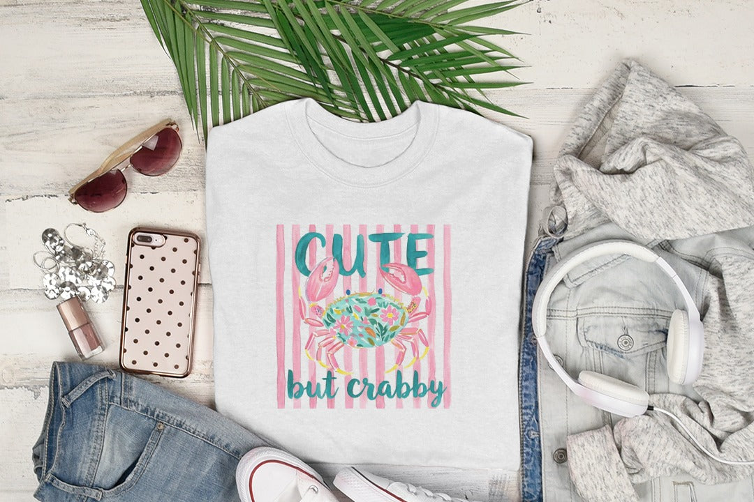 White t-shirt with pink crab graphic and "Cute but crabby" text.