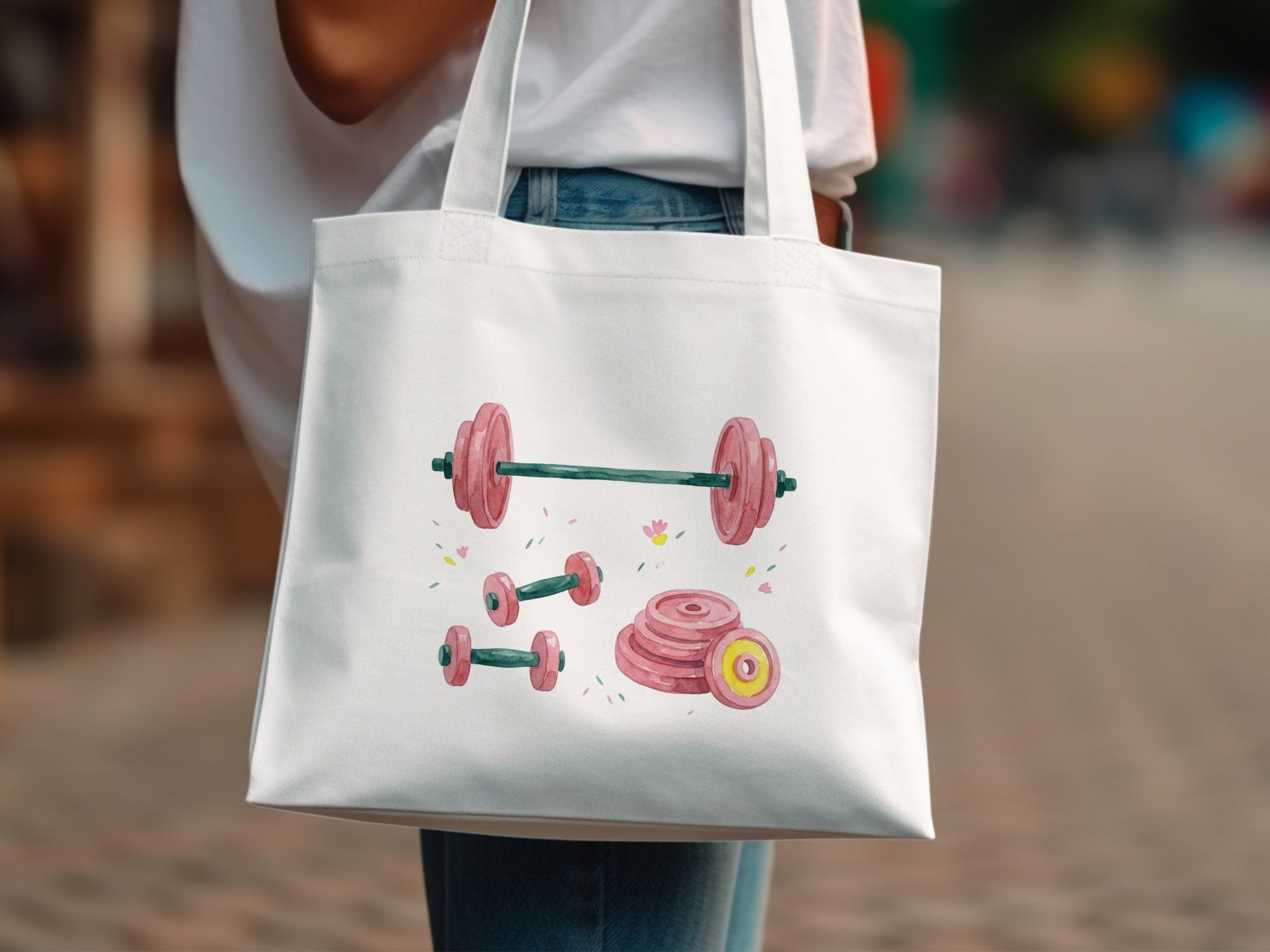 White tote bag with watercolor illustration of barbells and weight plates.