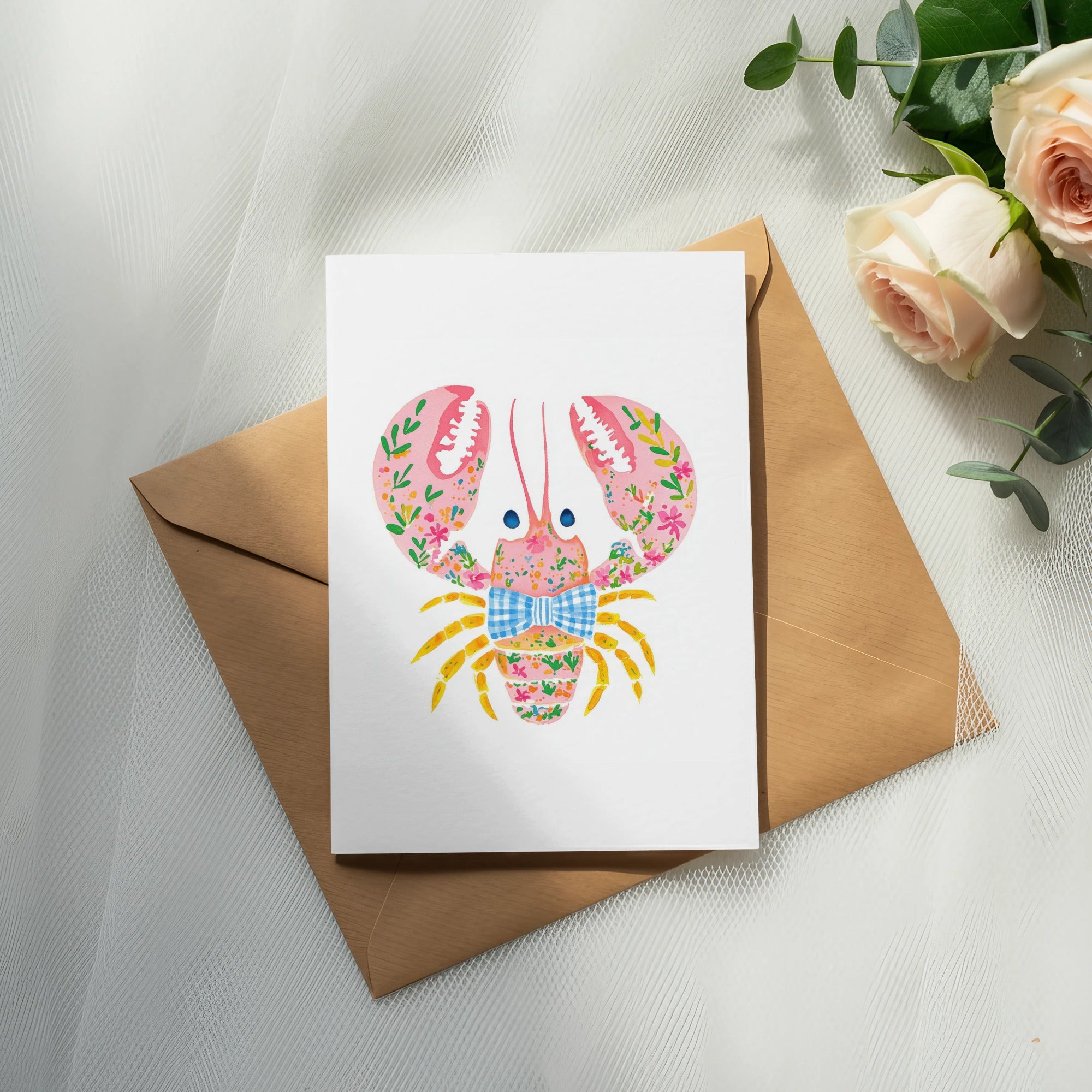 White card with pink floral lobster and blue plaid bow on brown envelope.