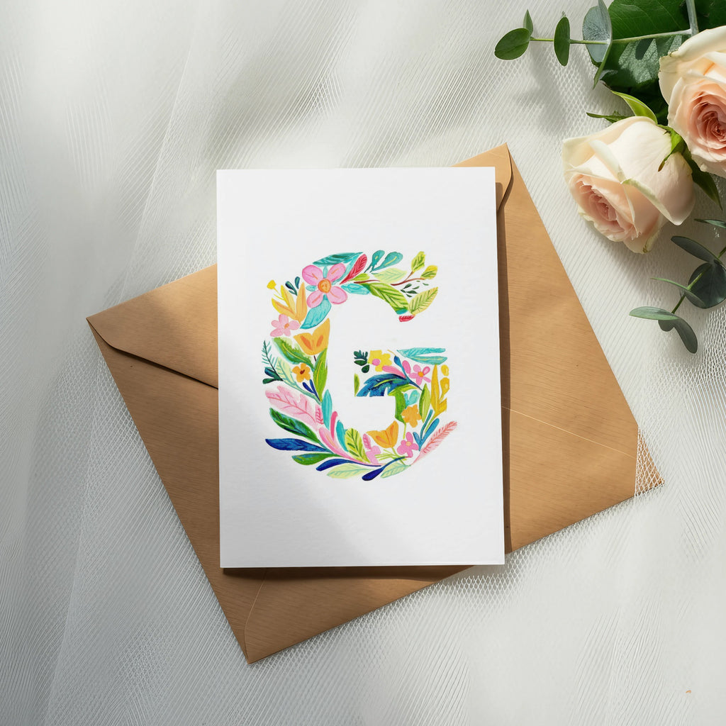 Card with colorful floral letter G on a brown envelope with roses.