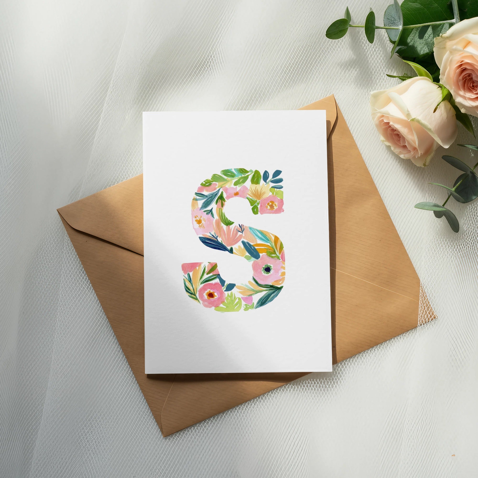 White card with letter S made of colorful flowers on brown envelope.