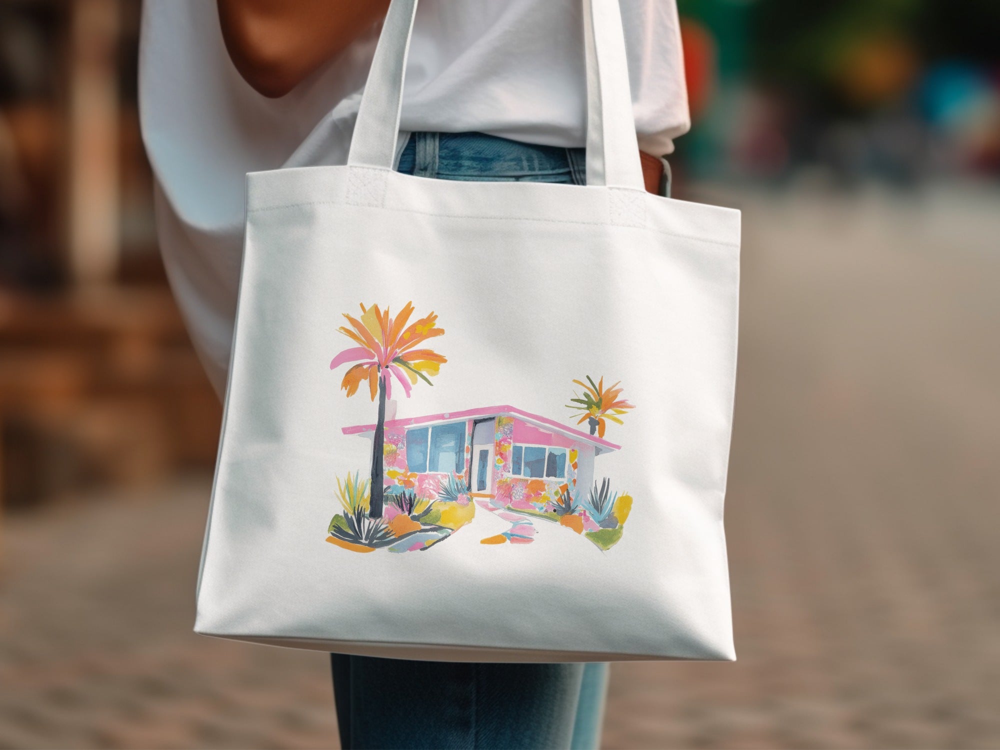 White tote bag with watercolor illustration of a pink mid-century modern house.