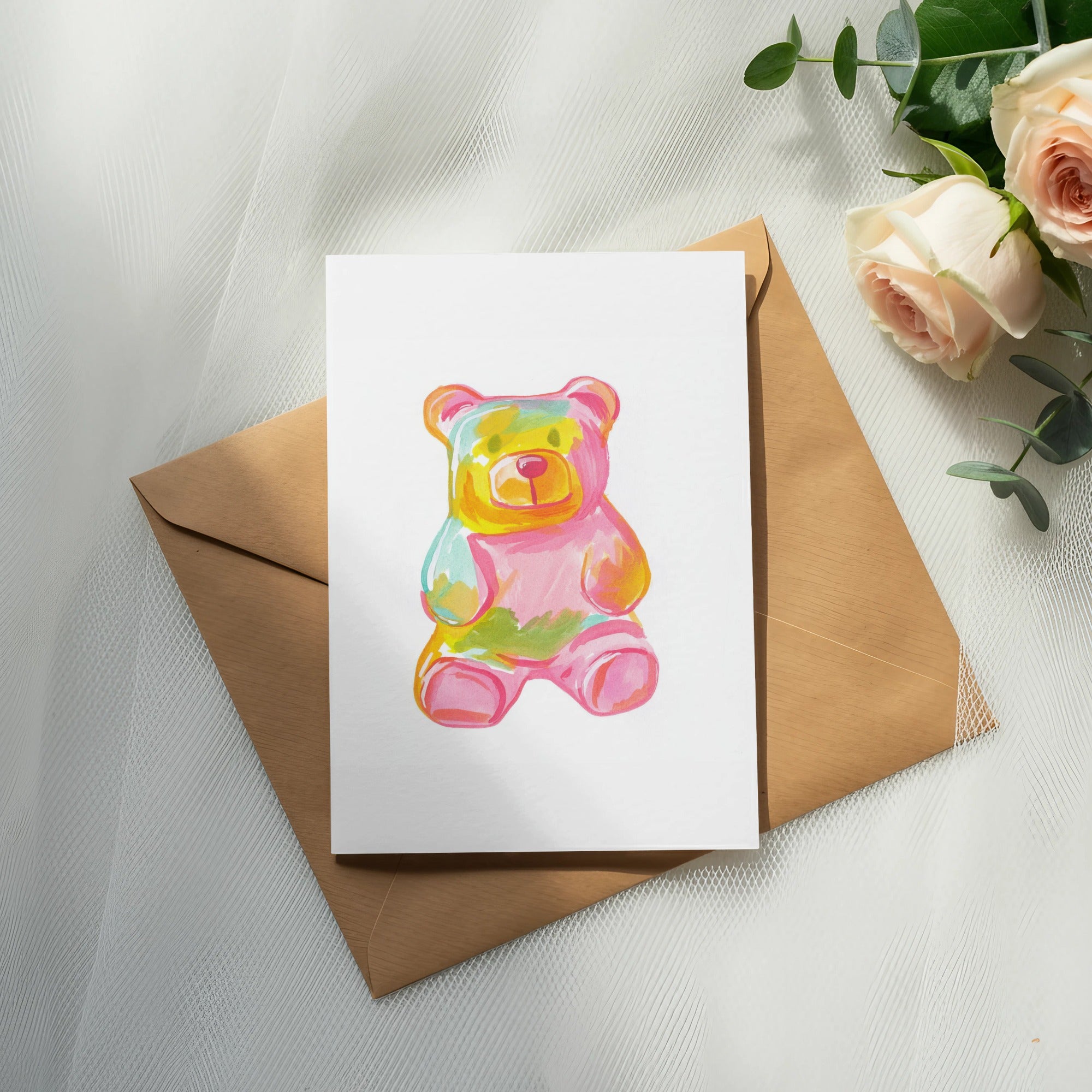 Gummy bear art on a card atop a brown envelope, with roses.