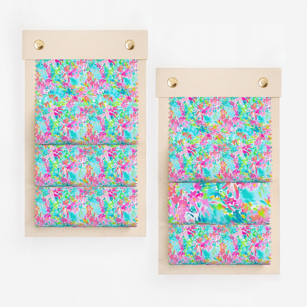 Two fabric swatches with colorful floral pattern on wooden displays.