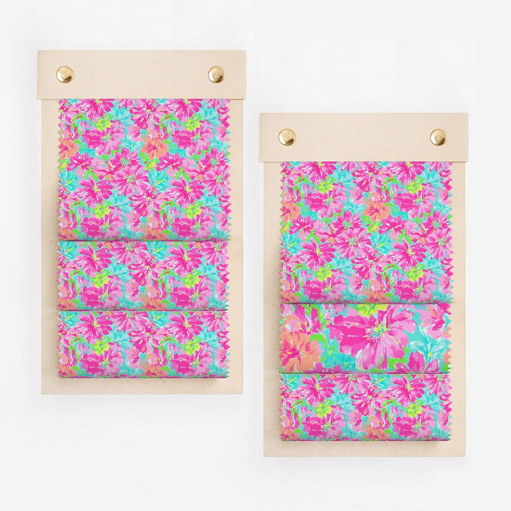 Two fabric swatches with a vibrant floral pattern in pink, blue, and green.