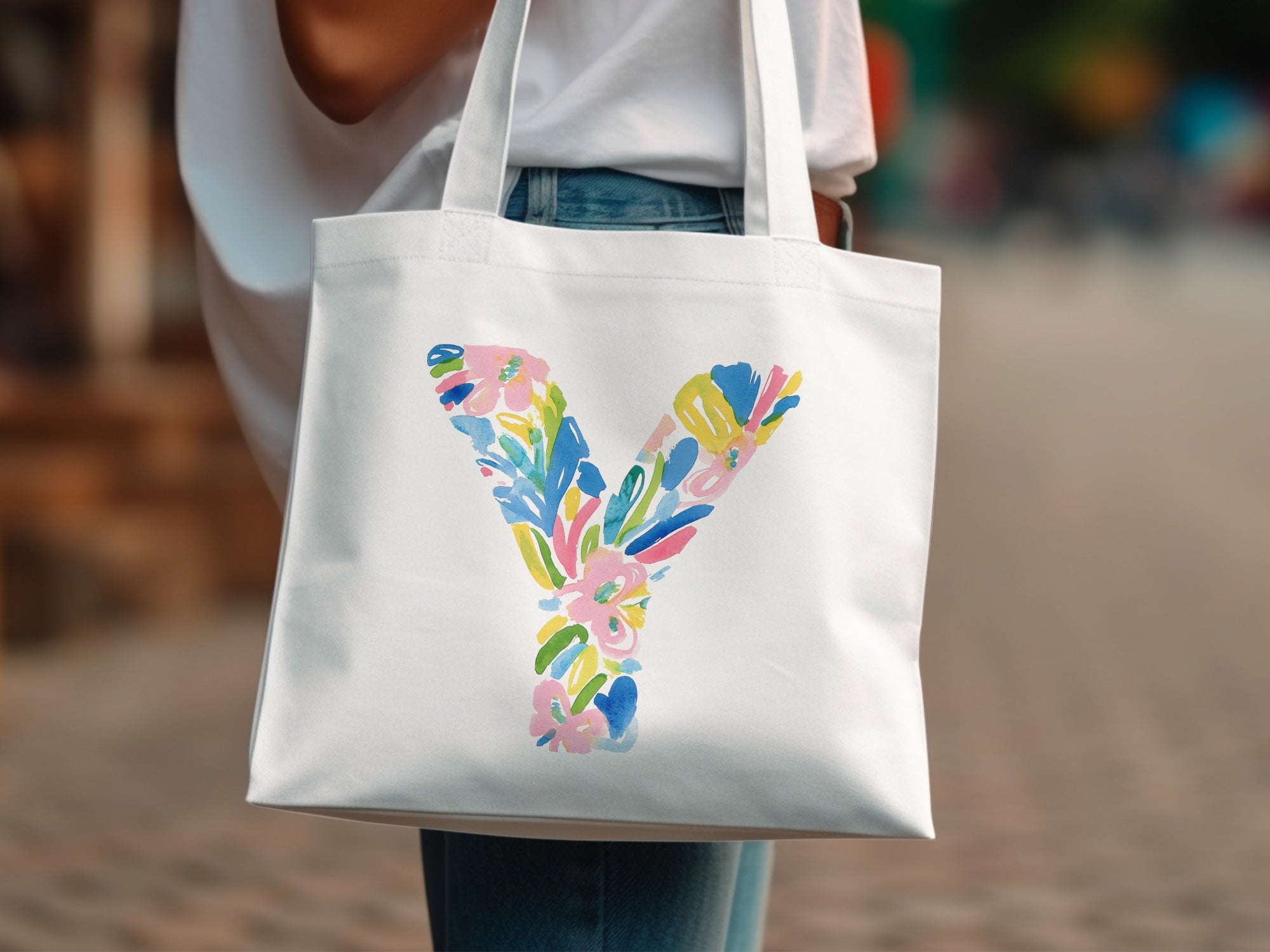 White tote bag with a colorful floral letter Y design.