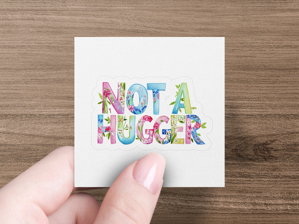 Floral letters spelling "NOT A HUGGER" held by a hand.