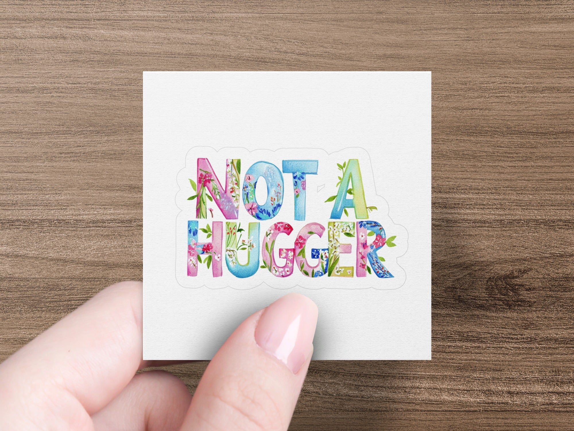 Floral letters spelling "NOT A HUGGER" held by a hand.
