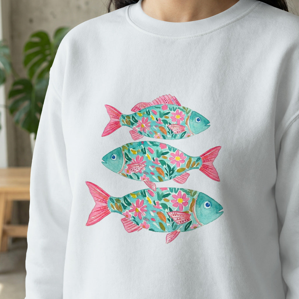 Three stylized turquoise fish with pink fins and floral patterns.
