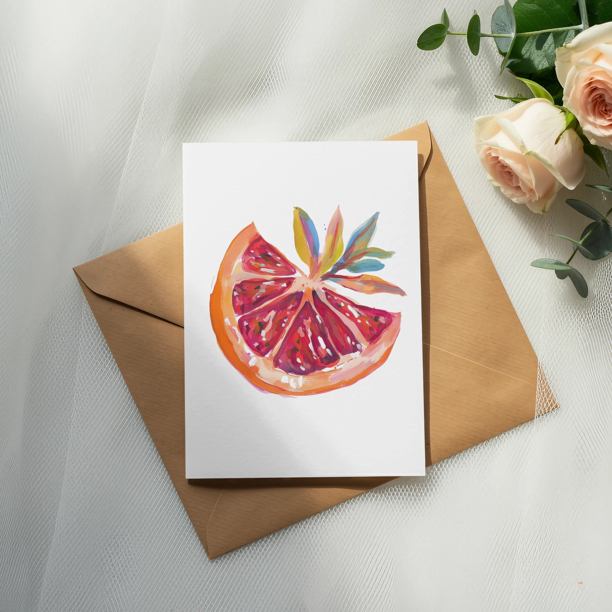 Watercolor painting of a grapefruit slice on a card, next to roses and eucalyptus.