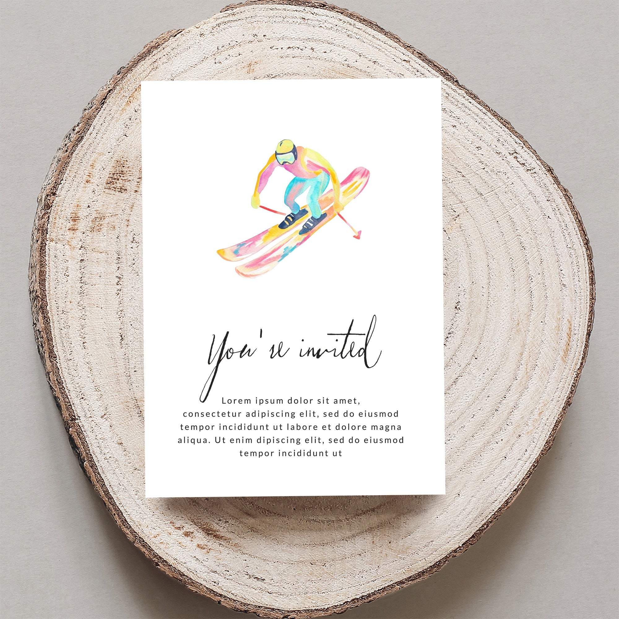 Watercolor illustration of a skier on a rustic wooden slice, with "You're invited" text.