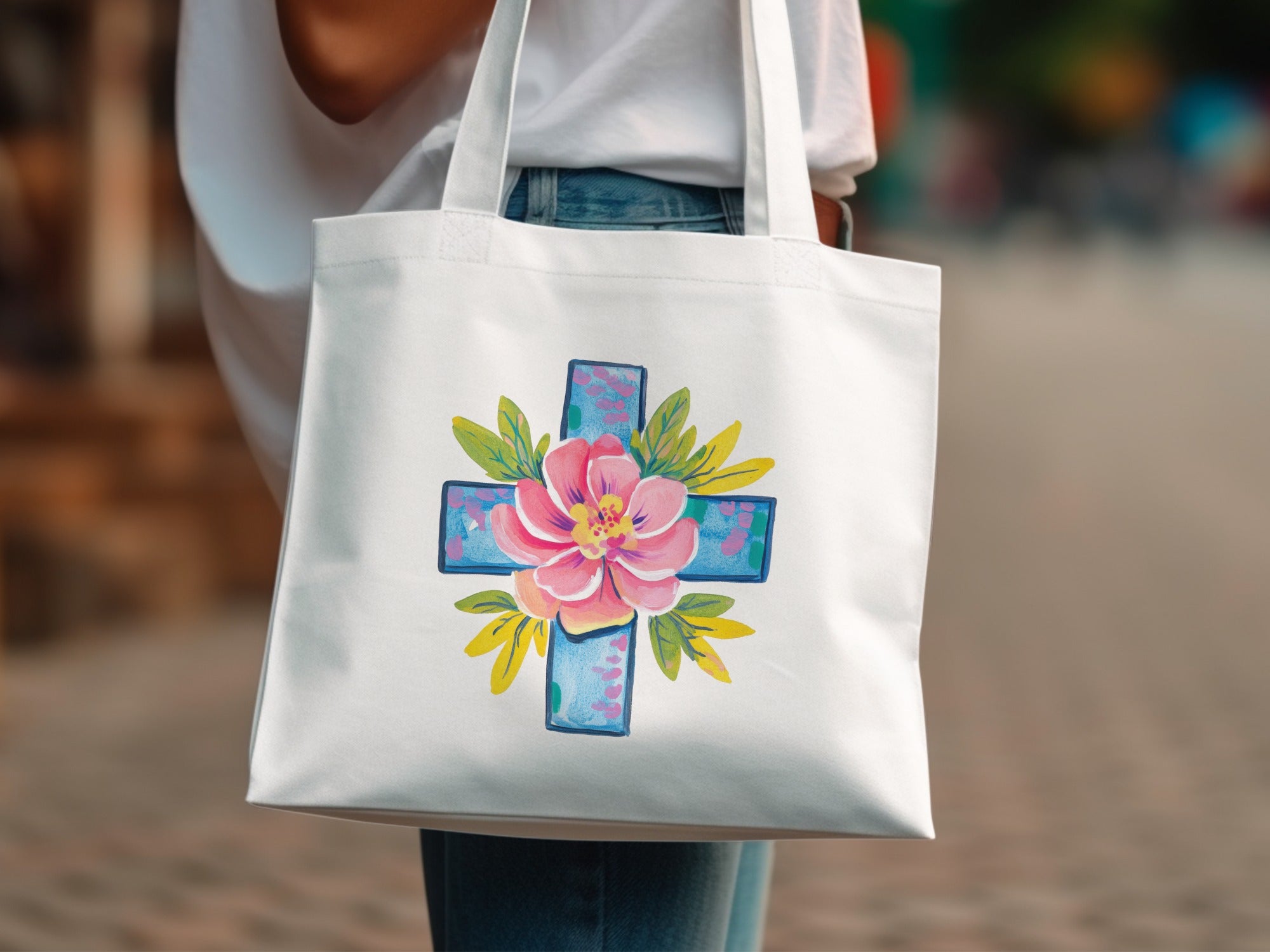 White tote bag with a pink and blue floral cross design.