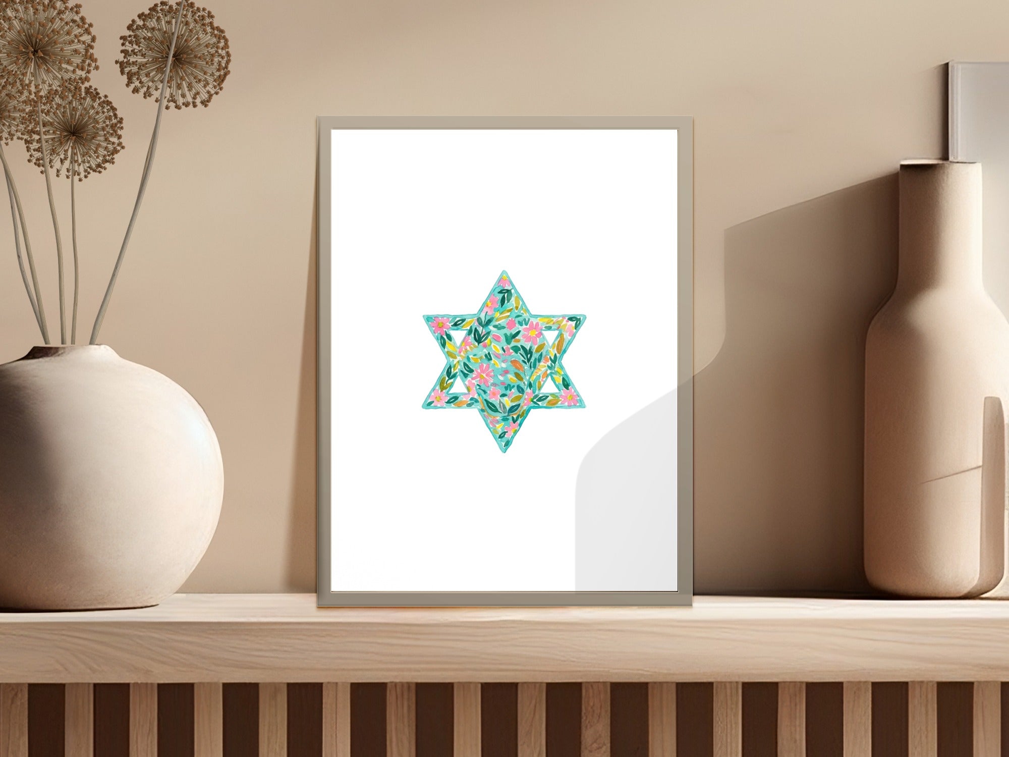 Star of David artwork with floral design in a frame on a shelf.
