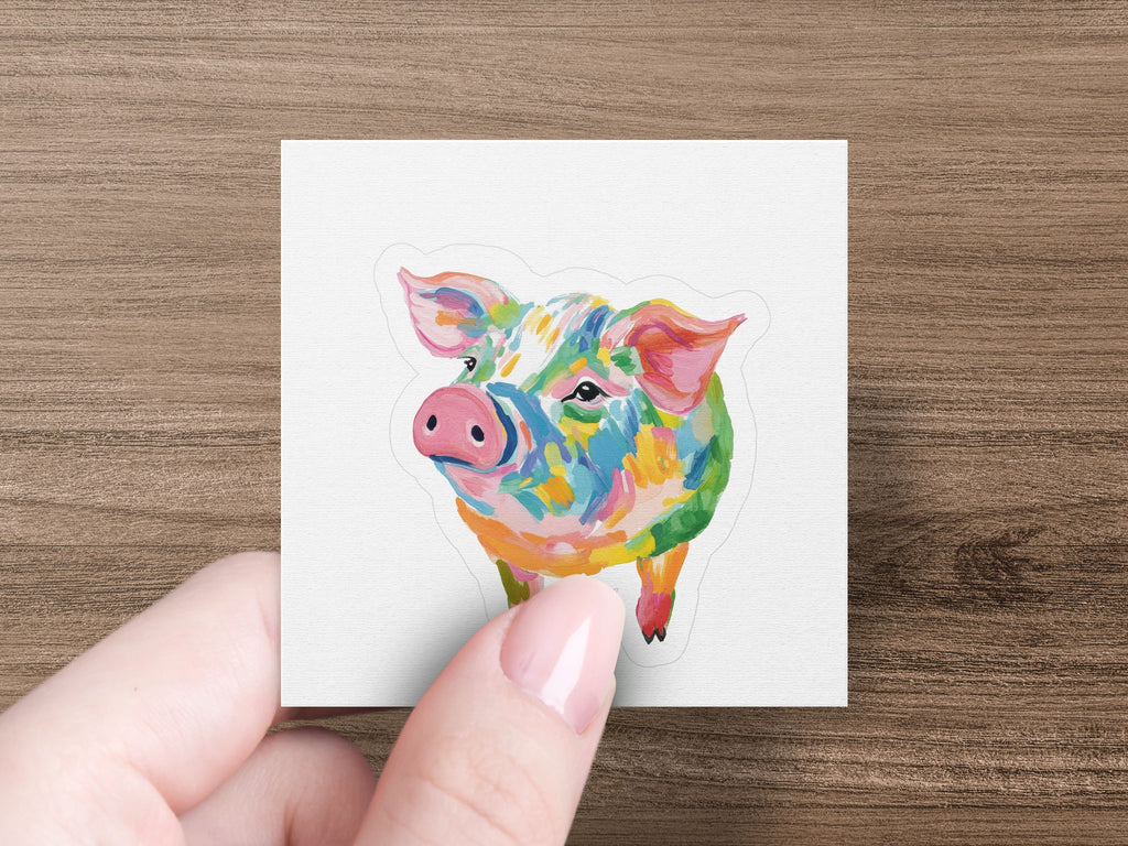 Colorful abstract pig illustration on a white square sticker held by a hand.