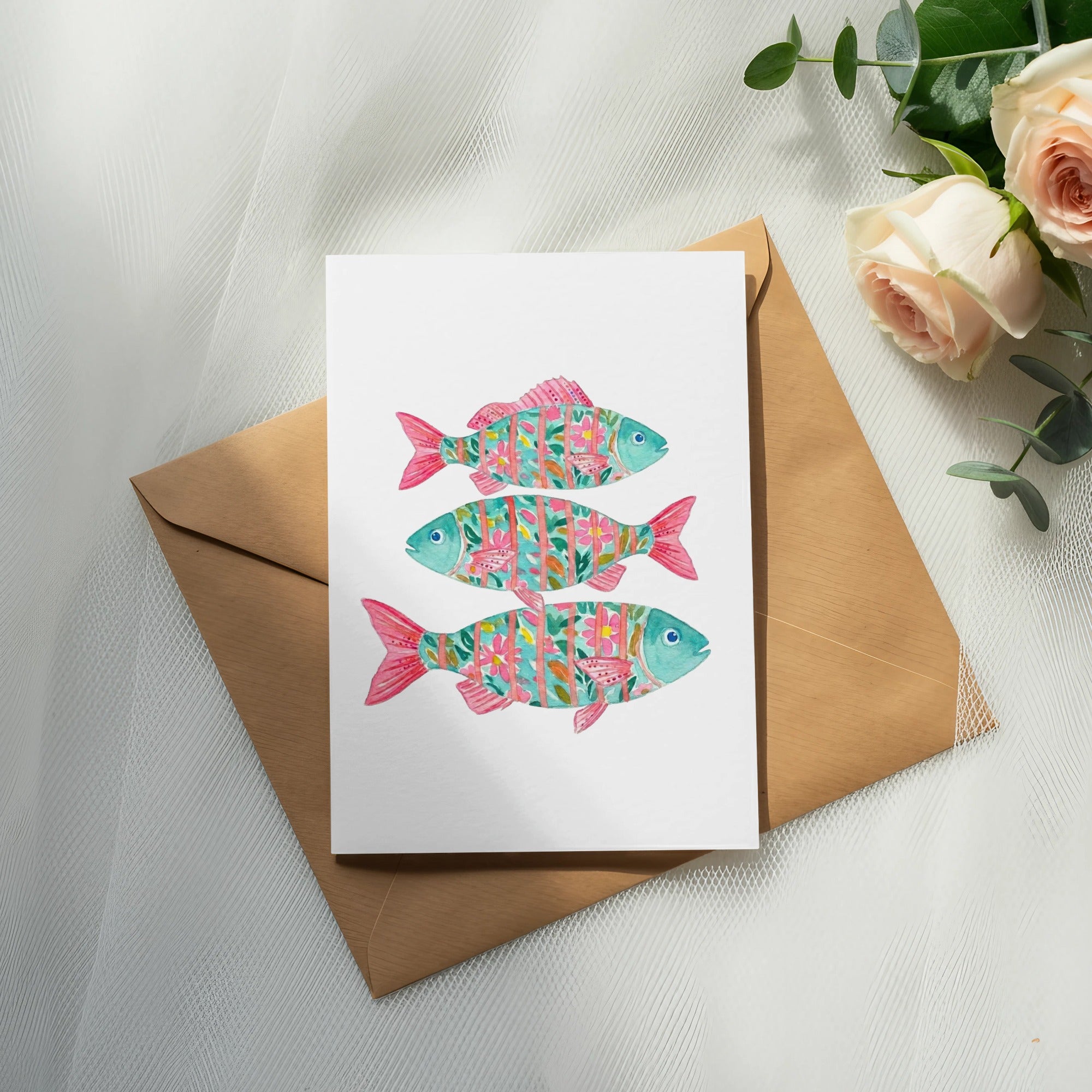 Watercolor card with three colorful fish and floral patterns on brown envelope.