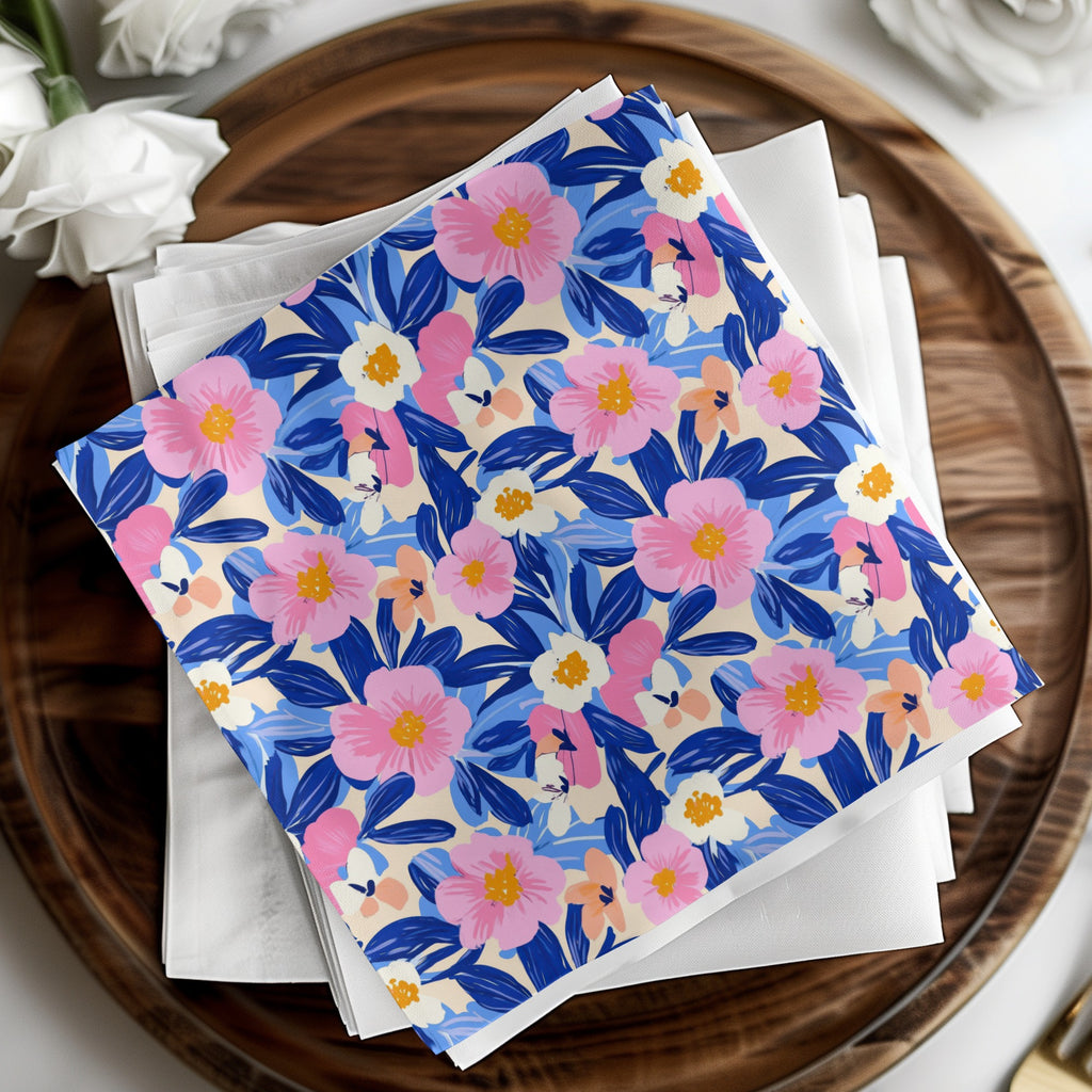 White napkins stacked with a colorful floral patterned cloth on a wooden tray.