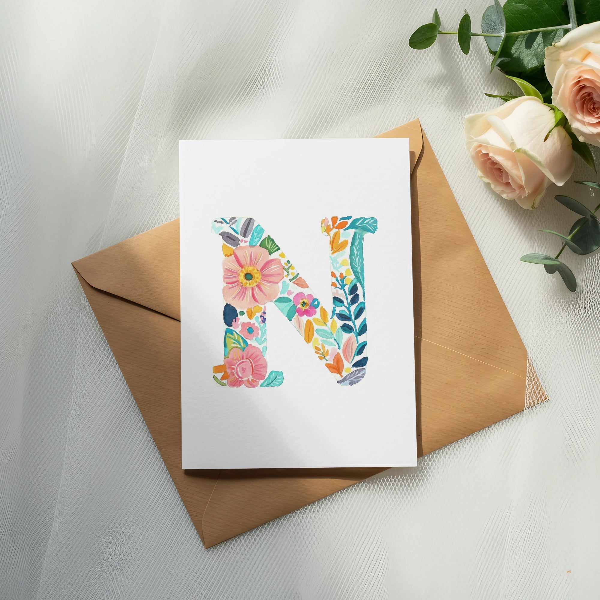 Floral letter N on card with envelope and roses.