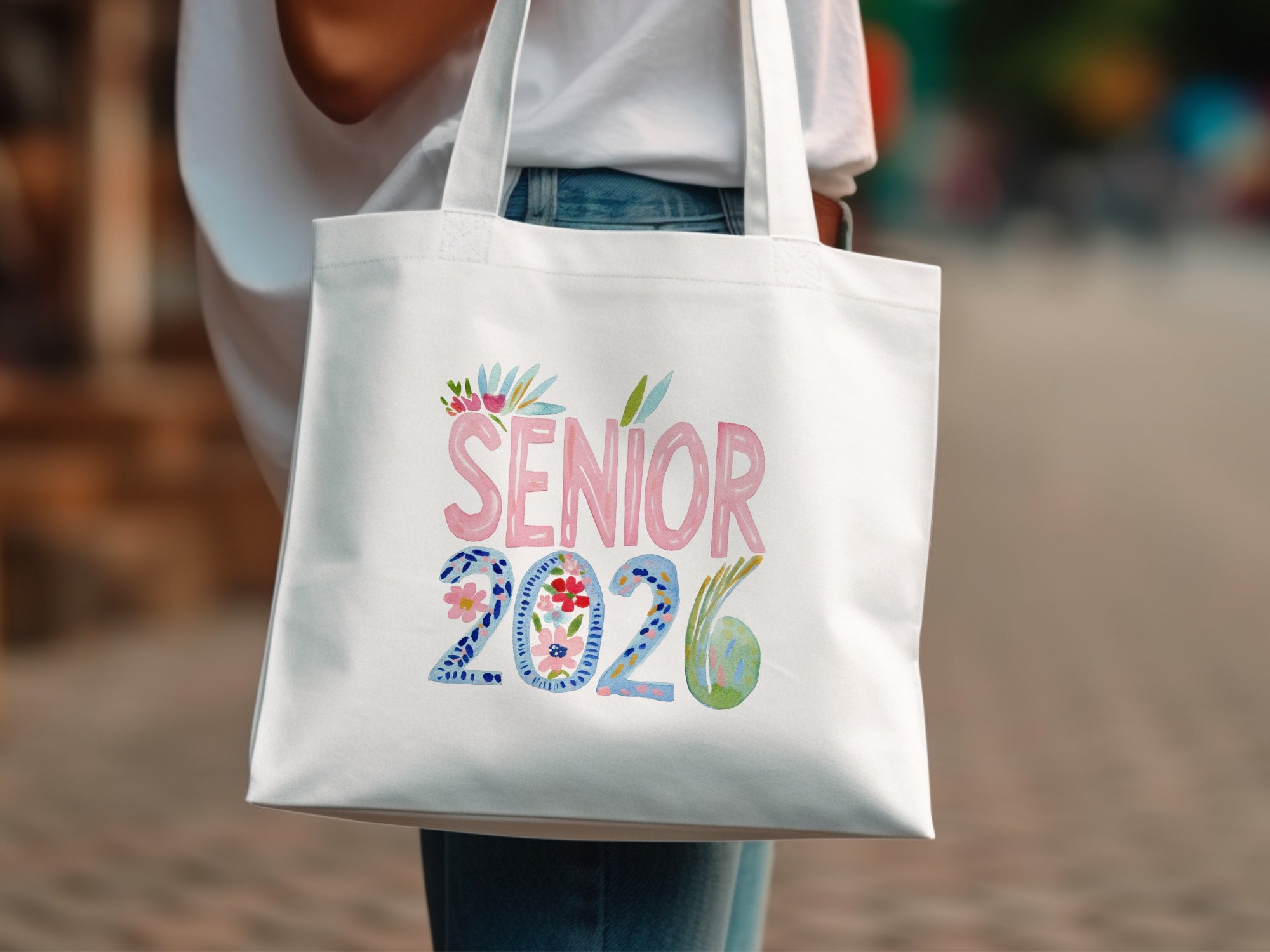 White tote bag with "SENIOR 2026" in colorful watercolor lettering and floral accents.