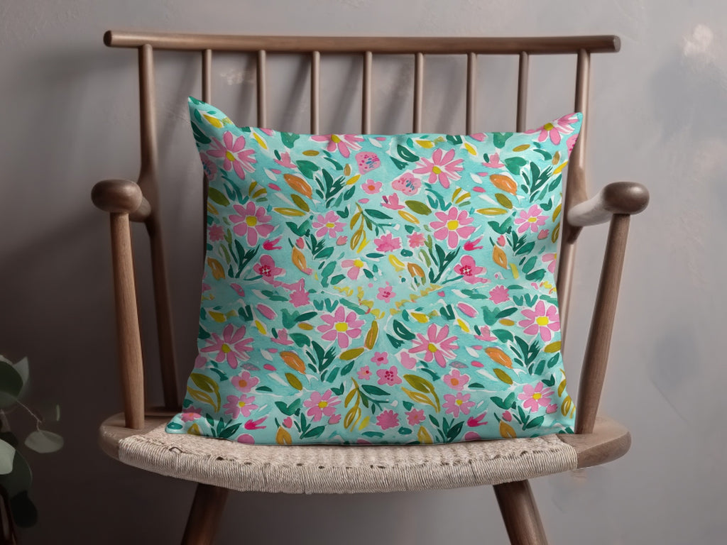 Teal throw pillow with pink and green floral watercolor pattern.