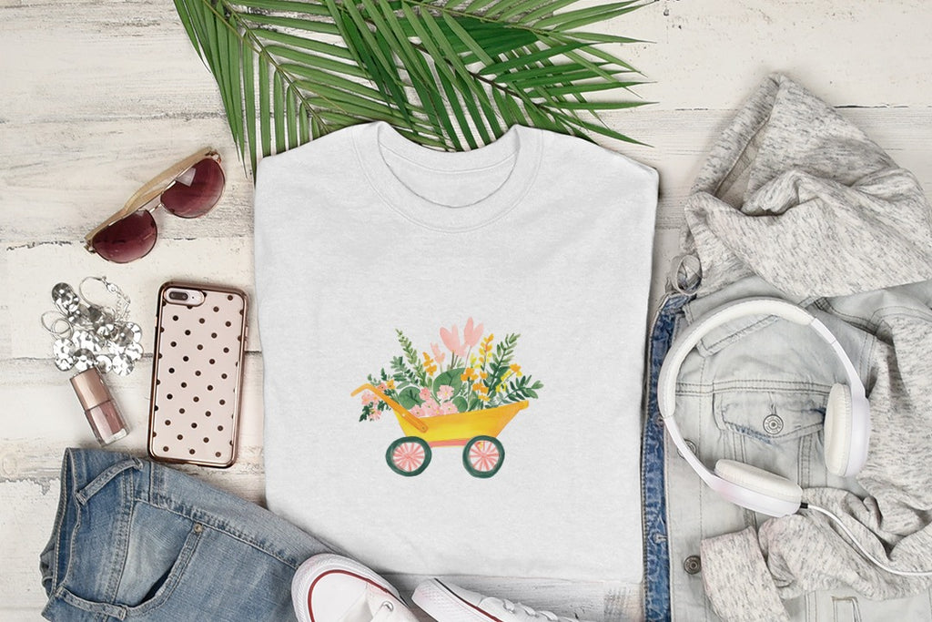 White t-shirt with yellow wheelbarrow filled with flowers and greenery.