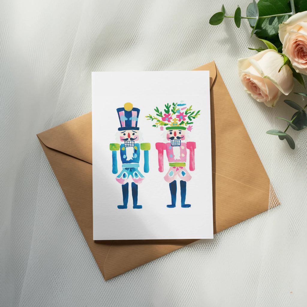 Two watercolor nutcracker figures, one with a hat, one with flowers, on a card.