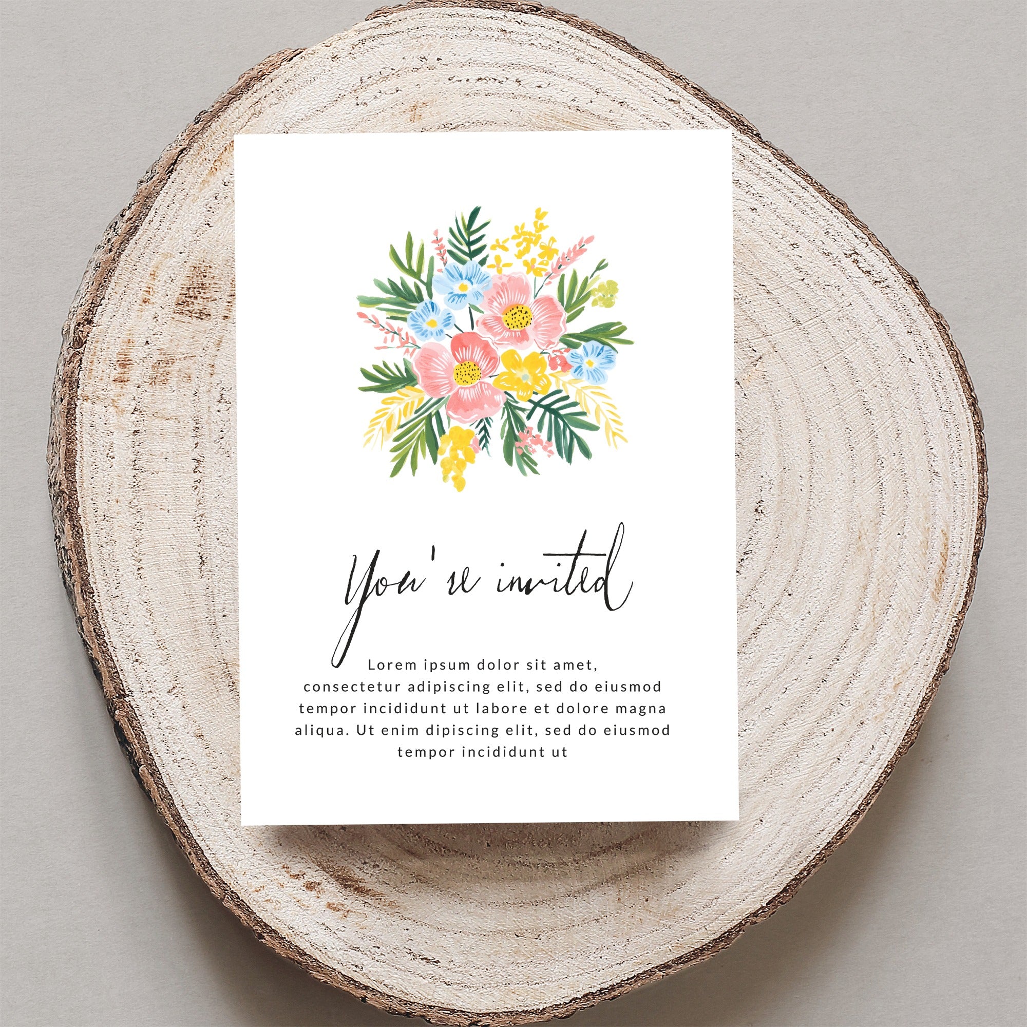 Invitation card with floral bouquet and "You're invited" text on wood.