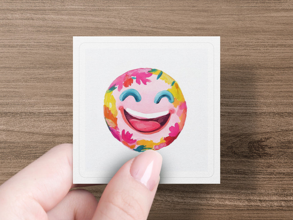 Smiling emoji with colorful floral accents, held by a hand.