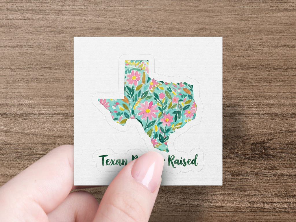 Texas shape sticker with floral pattern and text "Texan Raised".