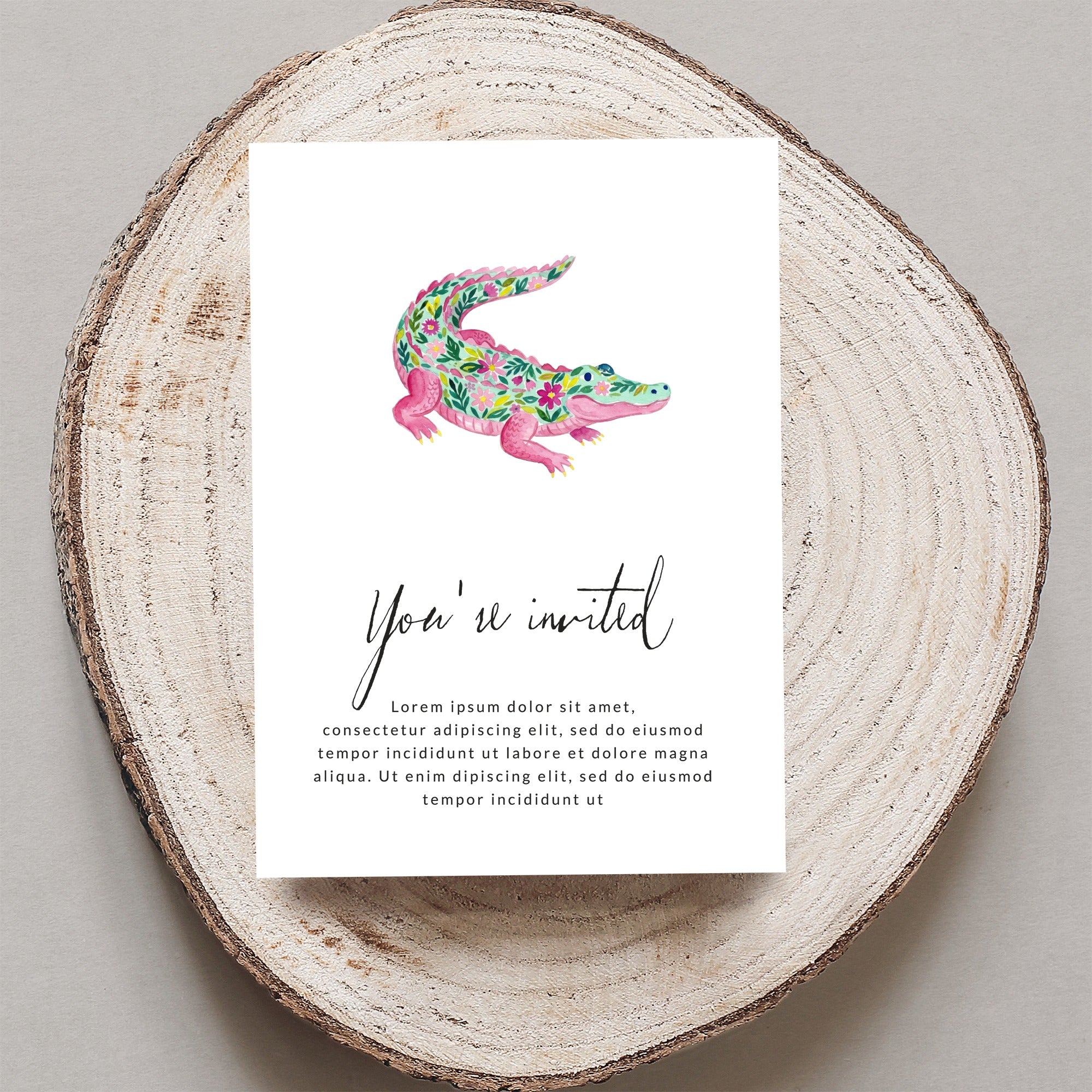 Pink alligator illustration on invitation with floral accents and placeholder text.