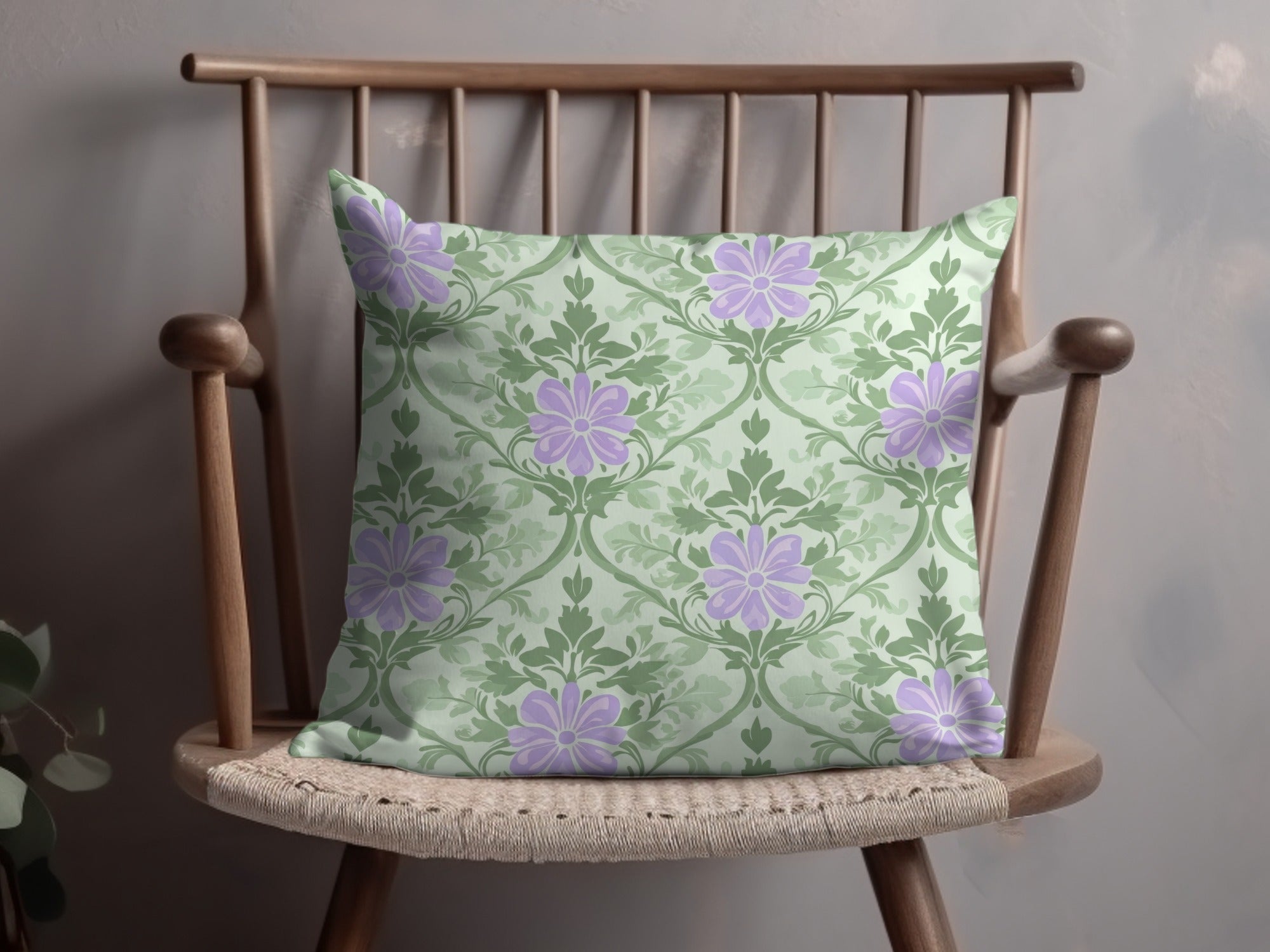 Light green throw pillow with a purple floral damask pattern on a wooden chair.