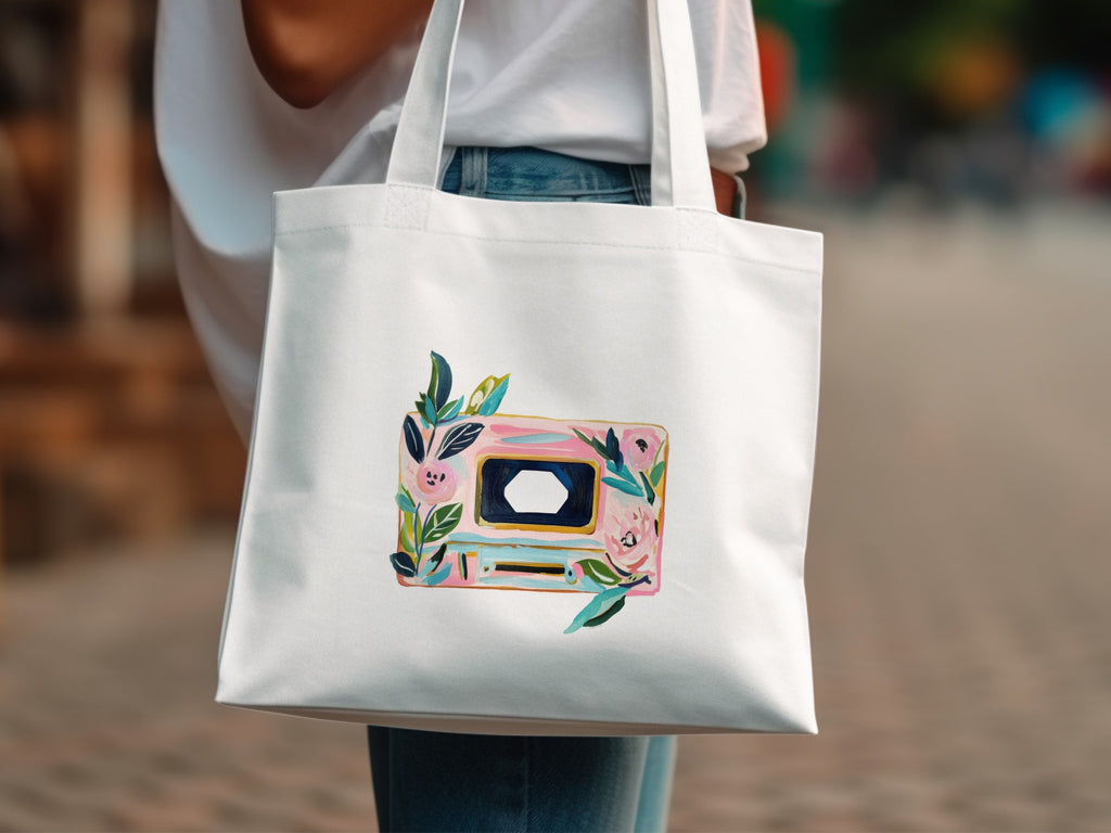 White tote bag with a painted cassette tape and floral design.