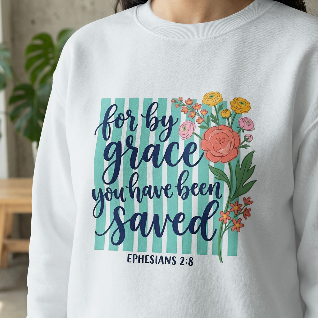 White sweatshirt with "for by grace you have been saved" in blue script and Ephesians 2:8.