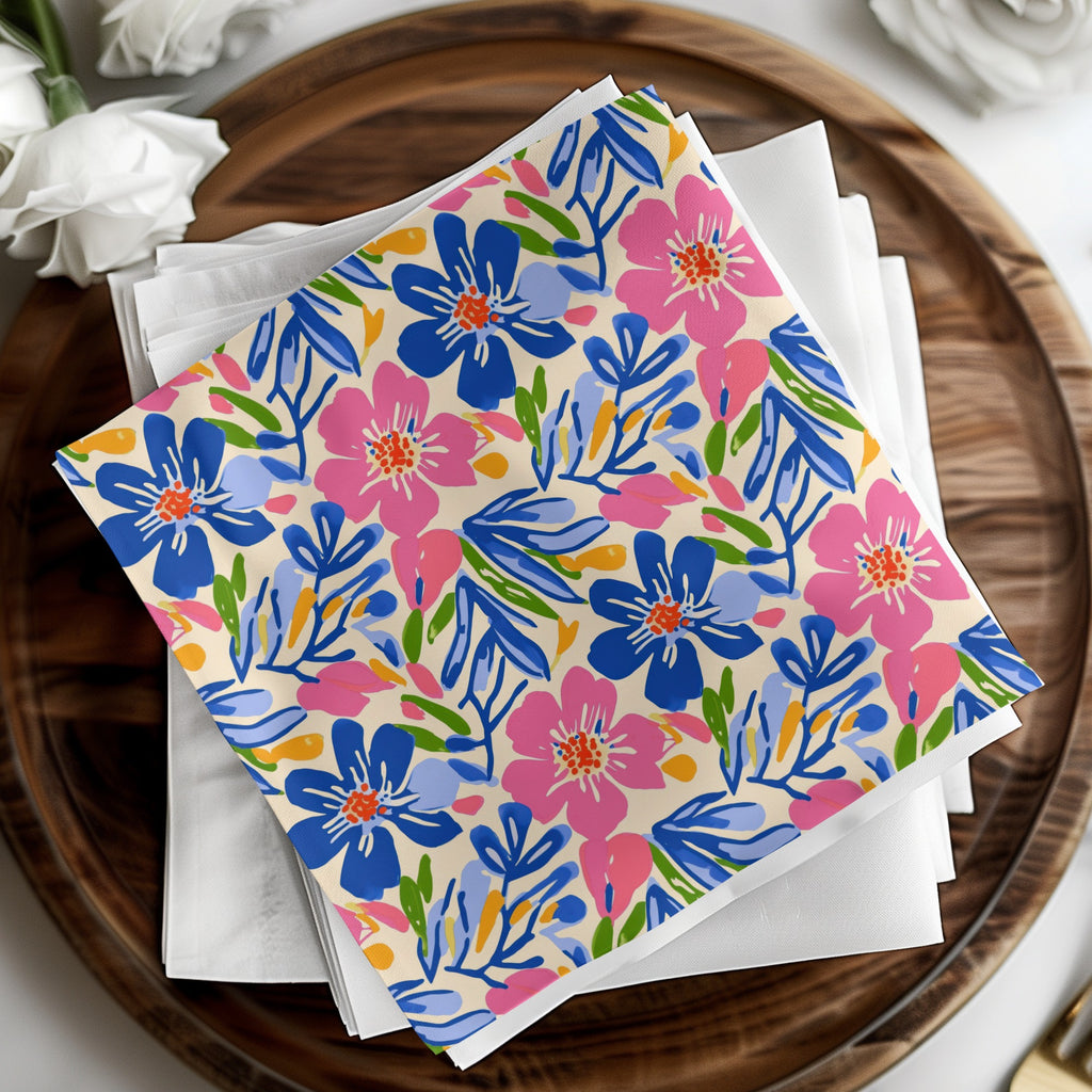 Colorful floral patterned napkins stacked on white napkins on a wooden tray.