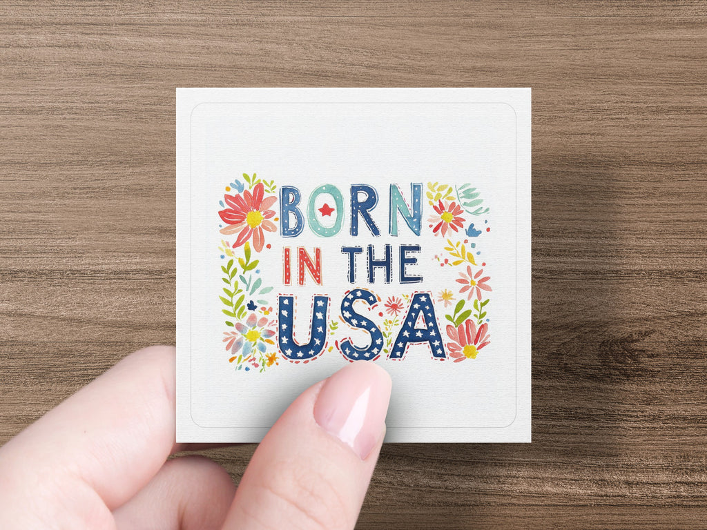 Square sticker with "BORN IN THE USA" text and floral accents.