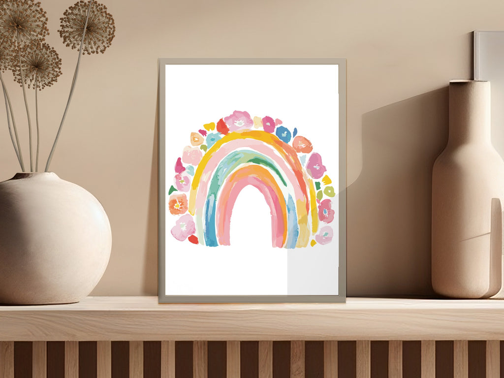 Watercolor rainbow with floral accents framed on a shelf.