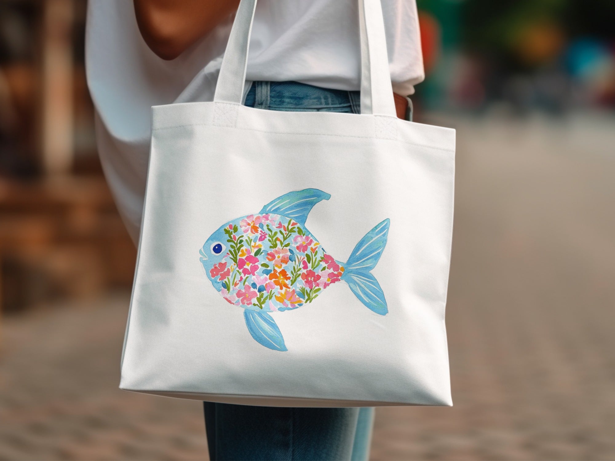 White tote bag with a watercolor fish design filled with colorful flowers.