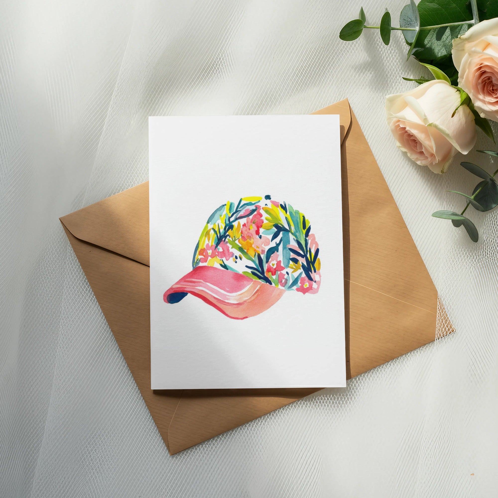 Watercolor painting of a floral baseball cap on an envelope with roses.