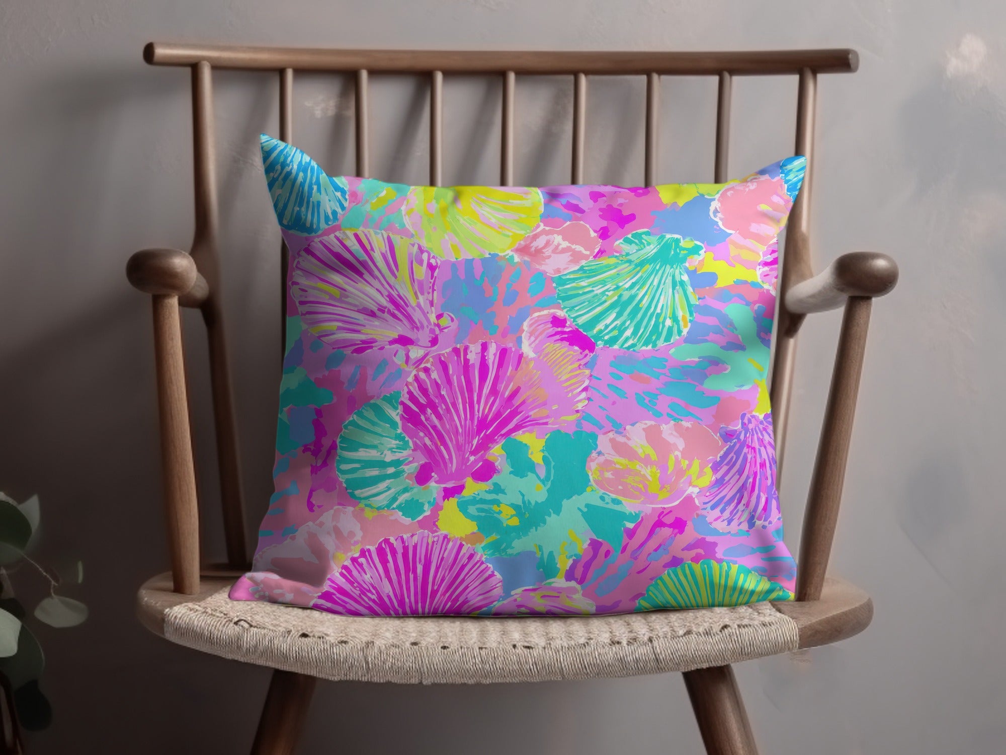 Colorful seashell pattern on a throw pillow on a wooden chair.