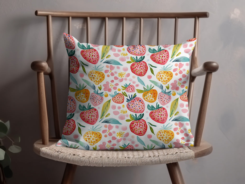 Pillow with watercolor strawberry and floral pattern on a wooden chair.