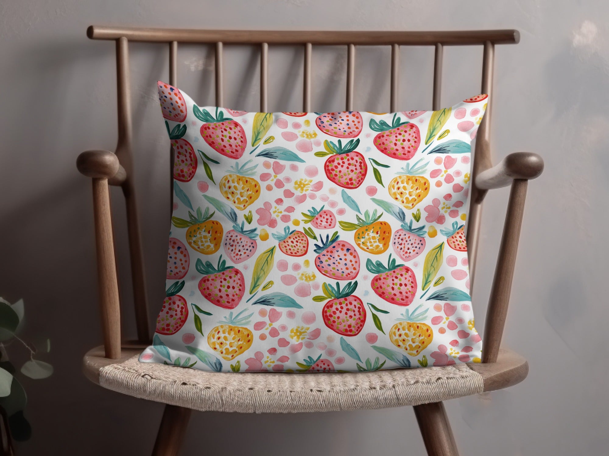 Pillow with watercolor strawberry and floral pattern on a wooden chair.