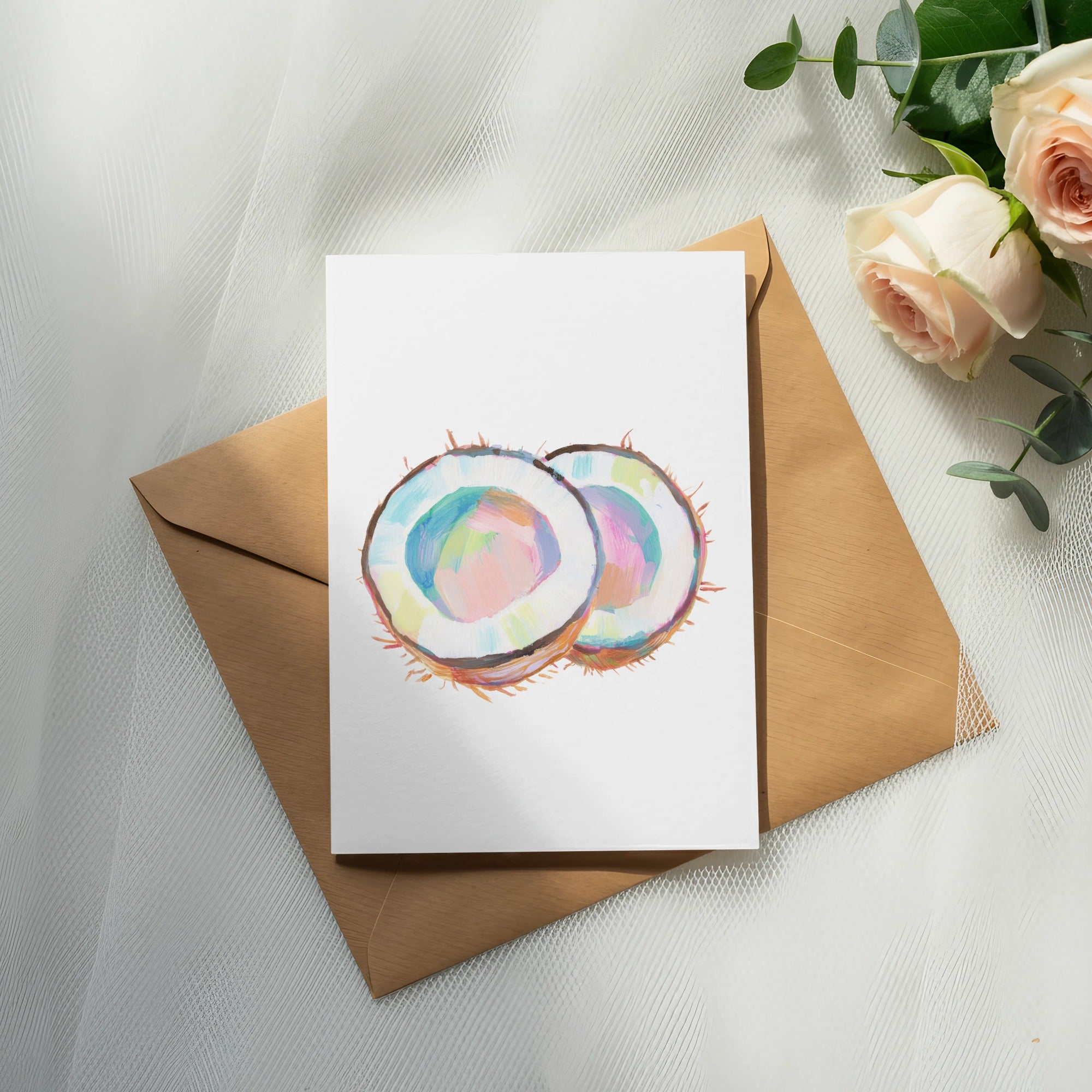Card with painted coconut halves on brown envelope with roses and eucalyptus.
