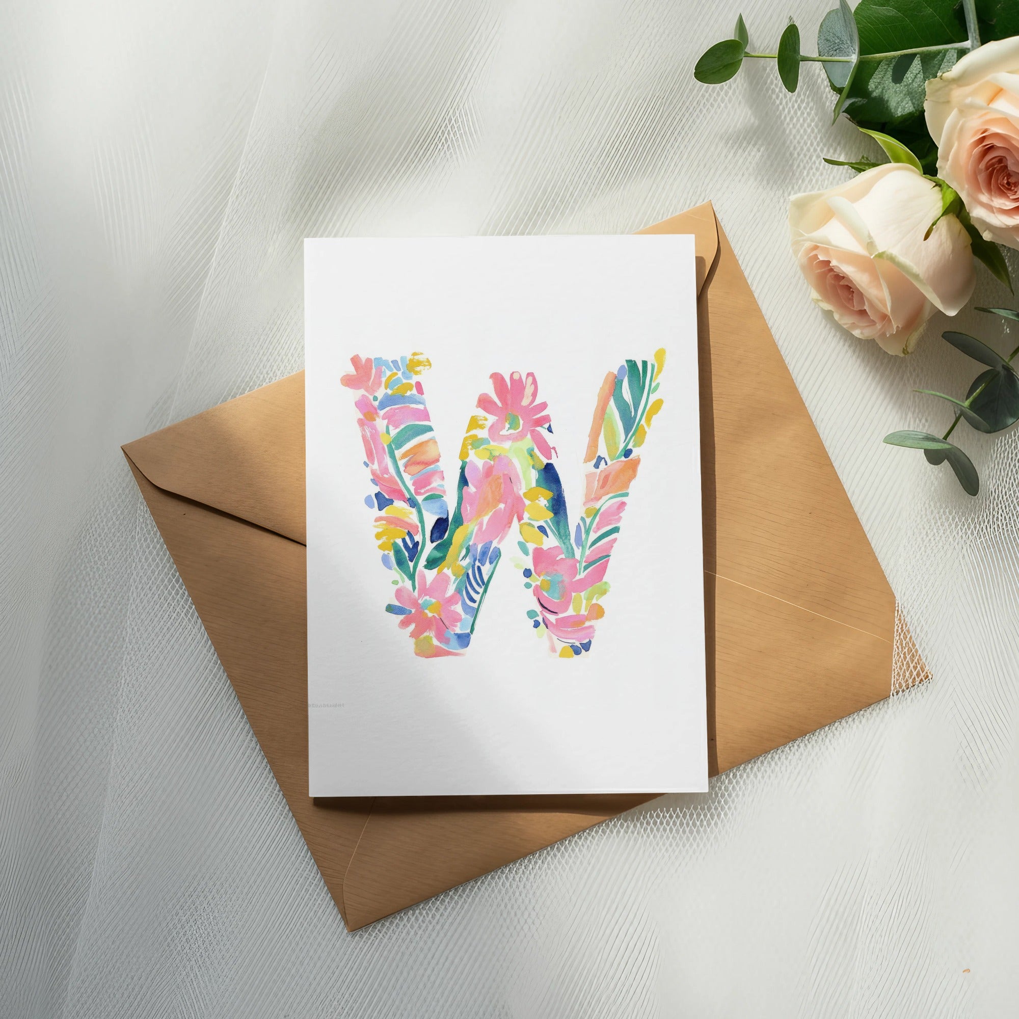 Card with a colorful floral letter W sits on an open envelope.