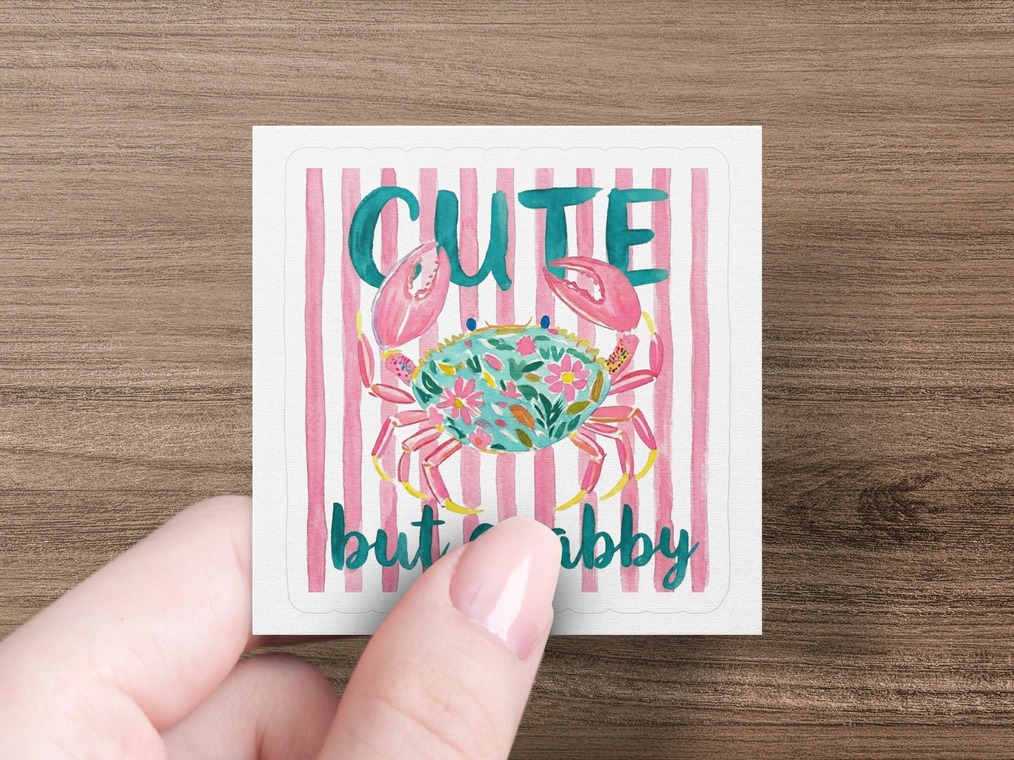 Pink and white striped background with a floral crab that says "cute but crabby".