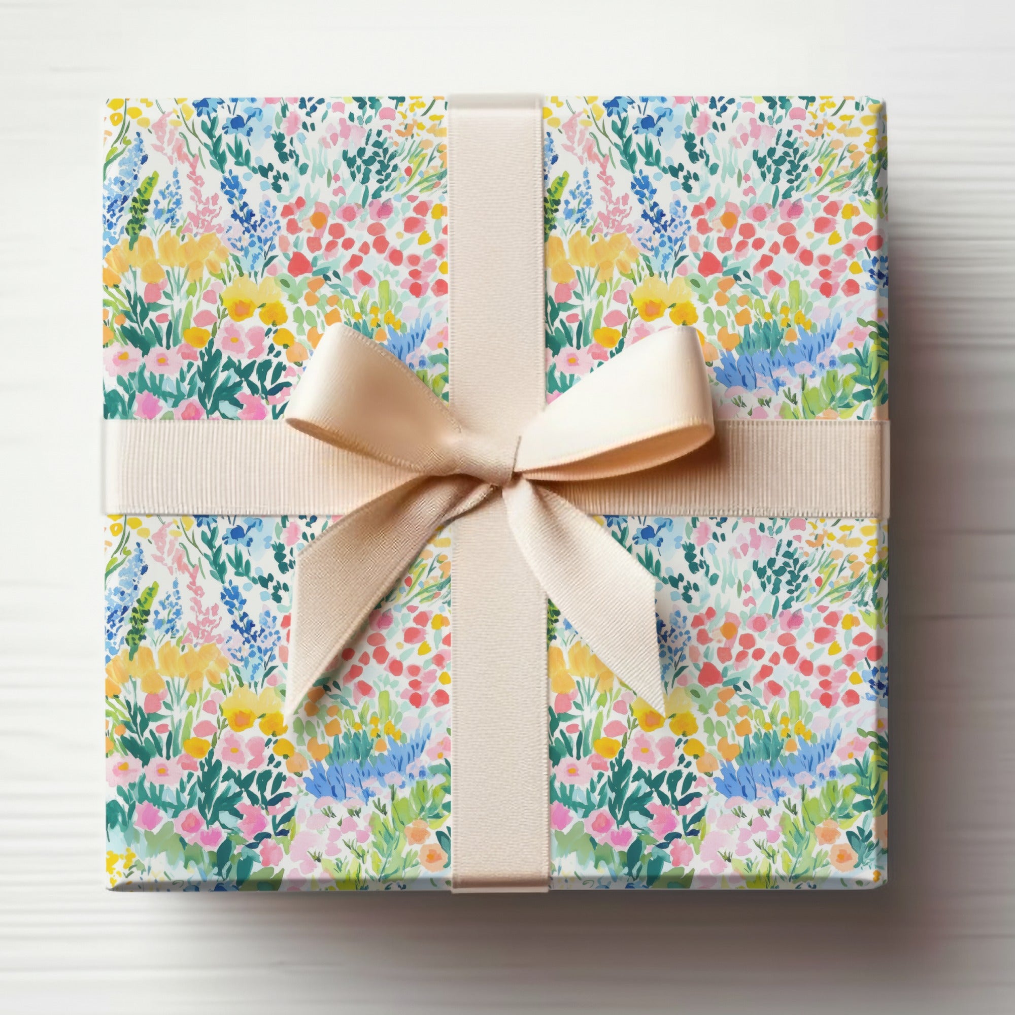 Wrapped gift box with colorful floral pattern and cream ribbon bow.