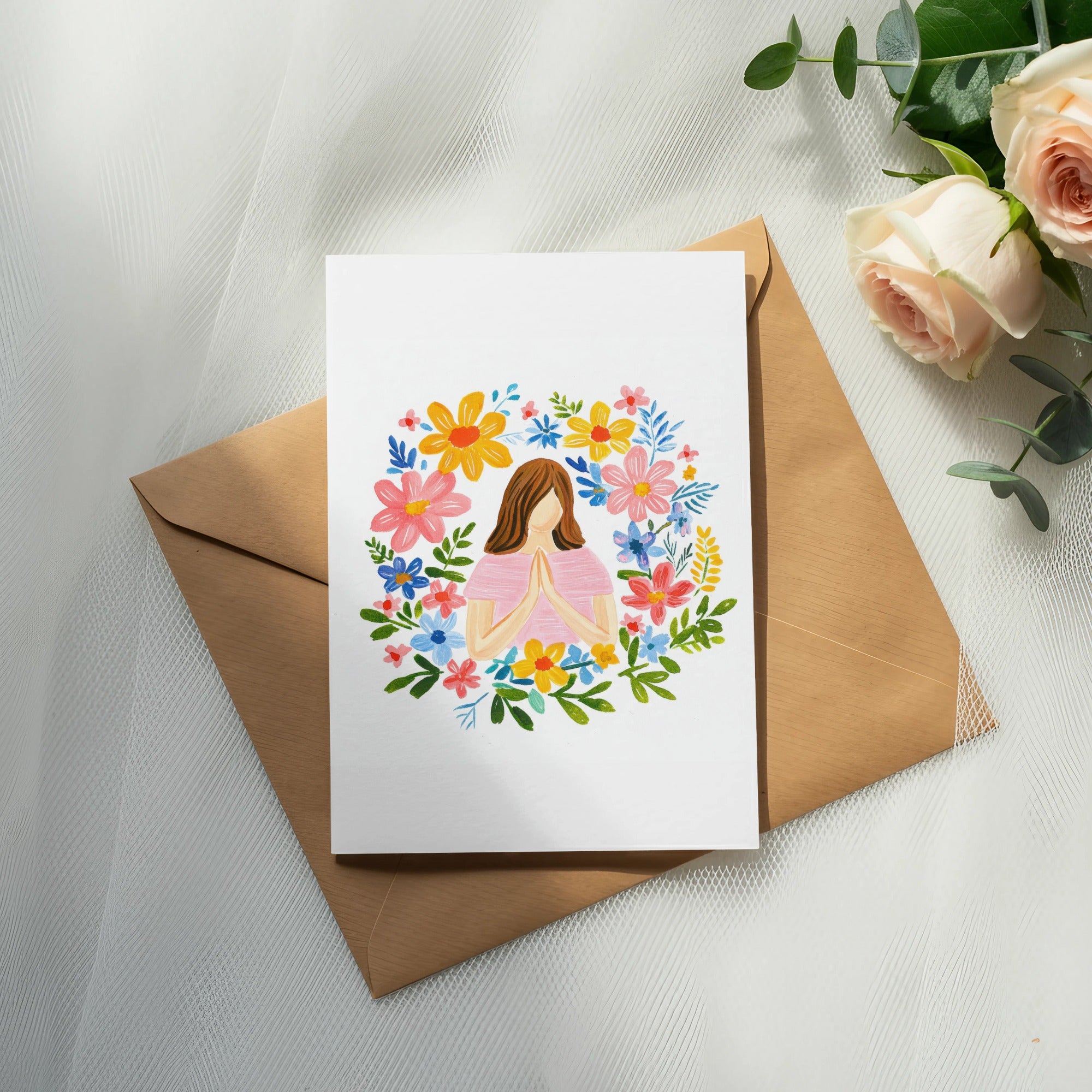 Greeting card with floral wreath and praying hands, on a brown envelope.
